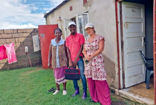 Drei Personen vor einem Haus